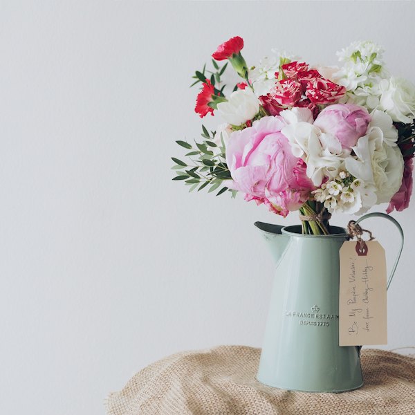 Bouquet de pivoines et d'œillets dans un broc, avec une étiquette