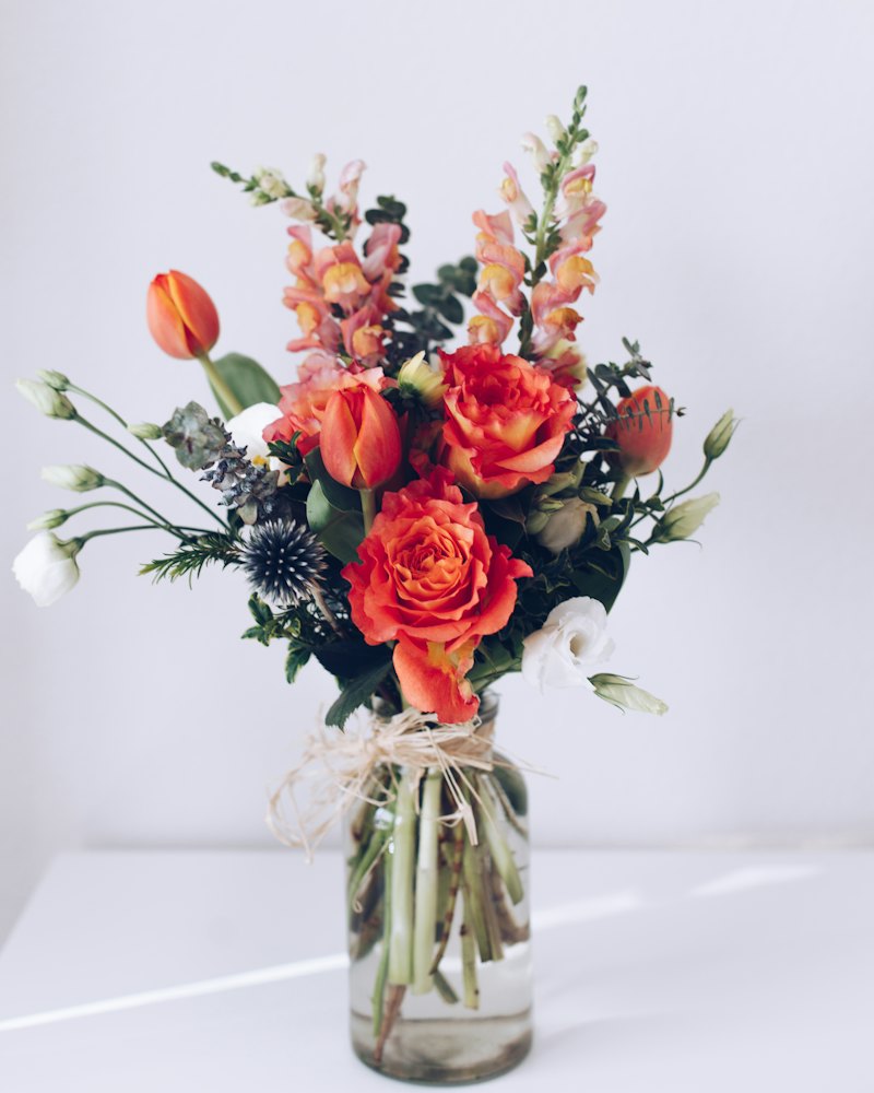 Bouquet coloré de roses rouges et de mufliers orangés dans un vase